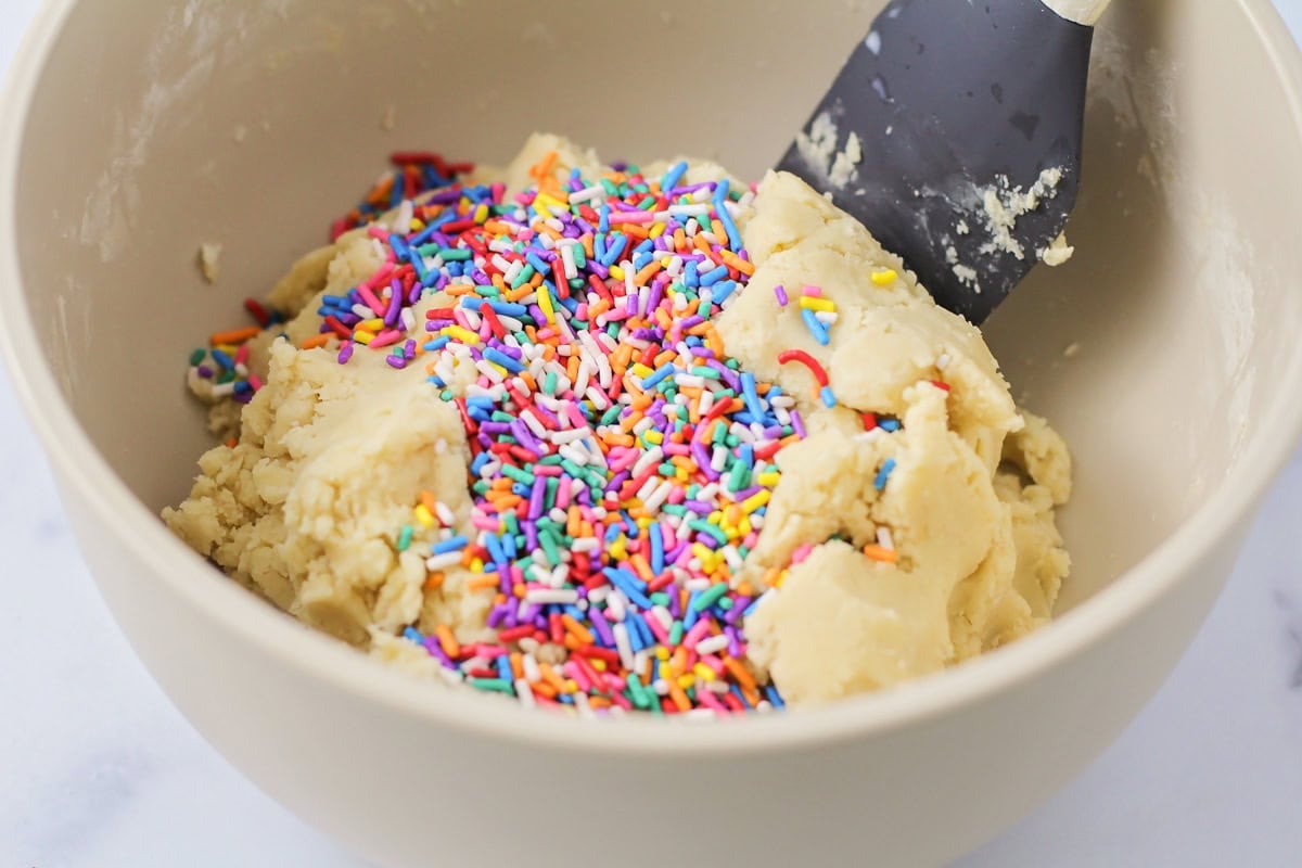 Adding sprinkles to sugar cookie dough.