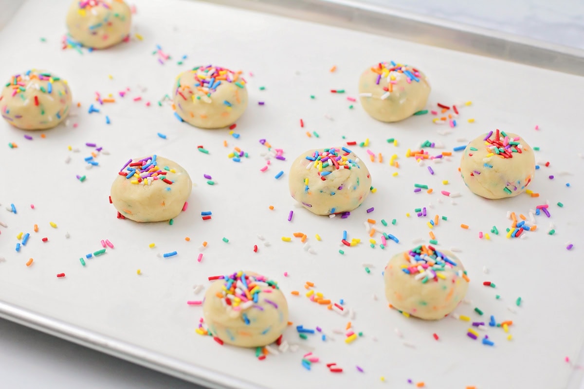 Sprinkle sugar cookie dough balls on a lined baking sheet.