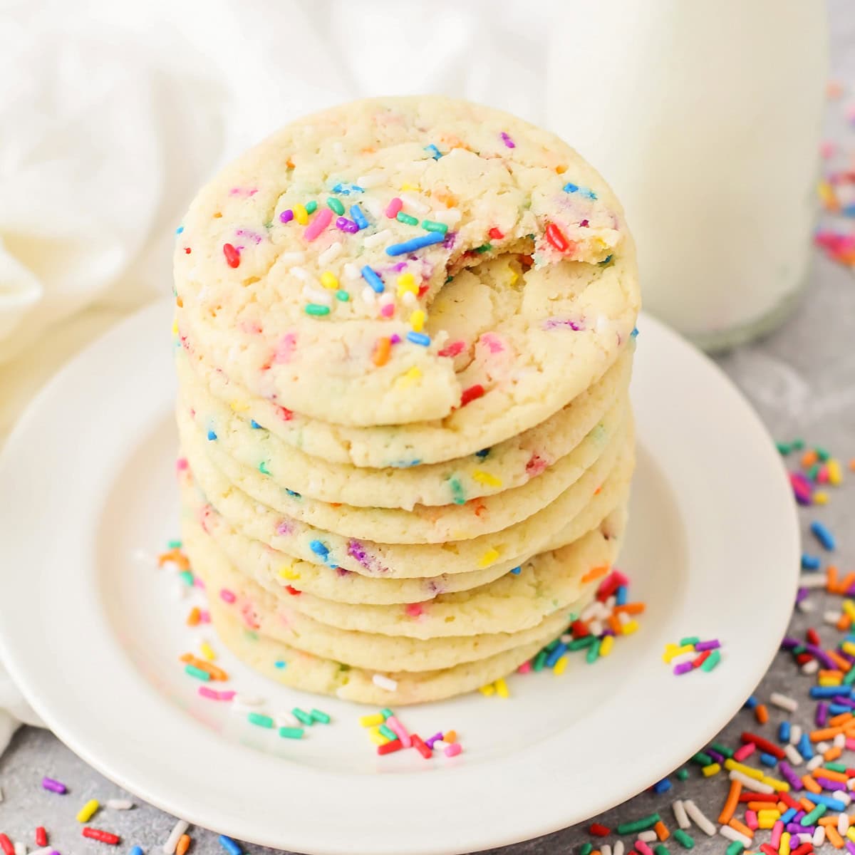 A stack of sprinkle sugar cookie with the top missing a bite.