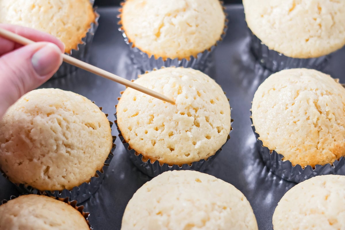 Poking holes in white cupcakes.
