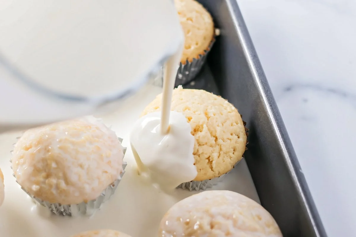 Drizzling cupcakes with milk mixture.