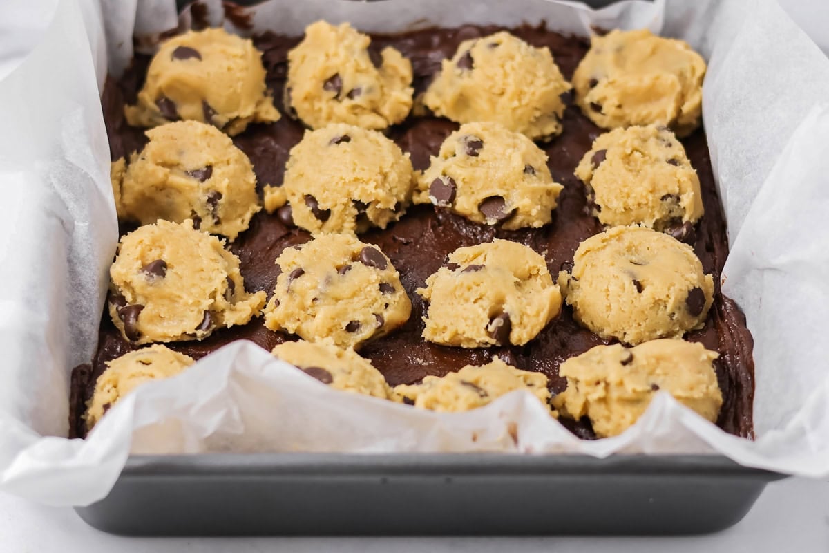 Dollops of cookie dough batter on top of brownie batter layer.