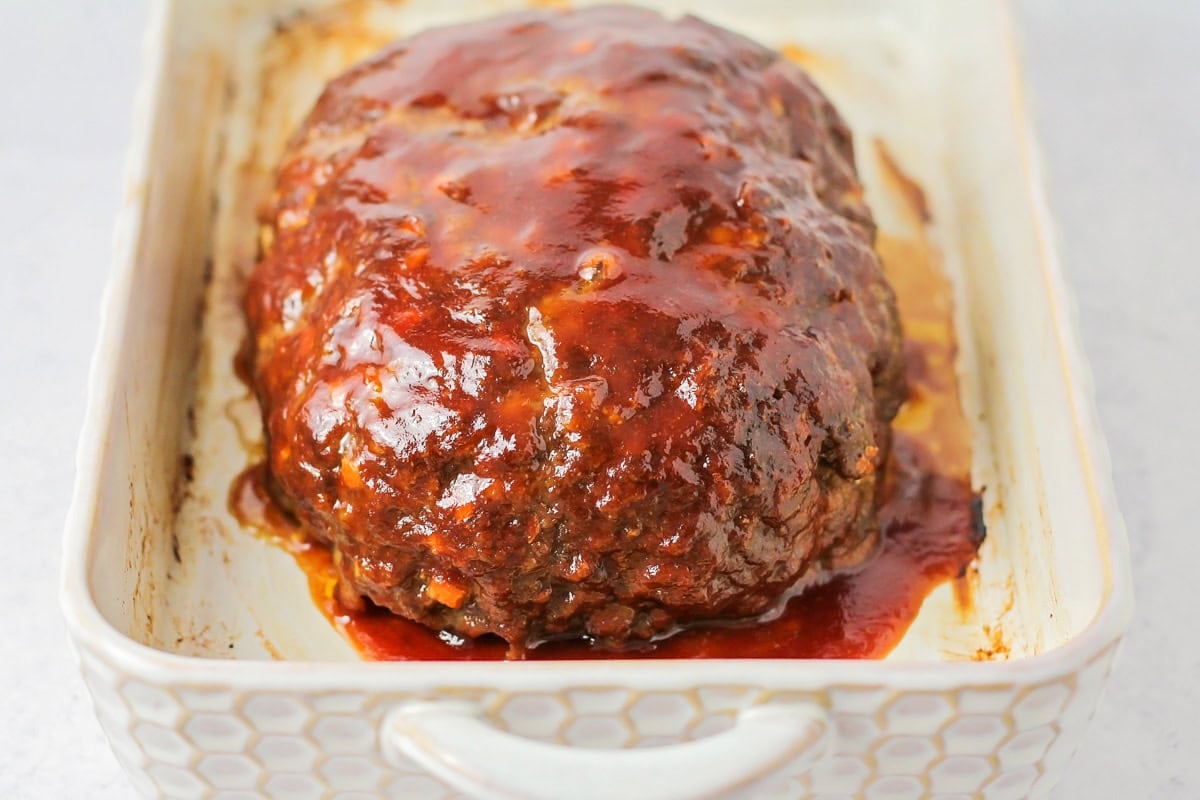 Easy homemade meatloaf recipe with sauce on top in baking dish.