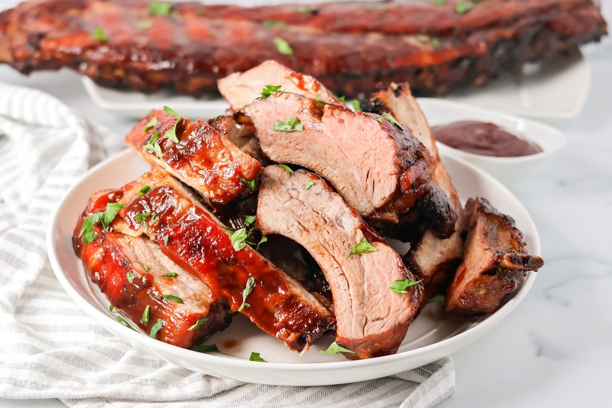 A plate of easy ribs served with bbq sauce.