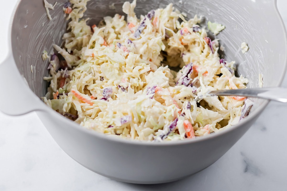 Mixing a slaw in a gray bowl.