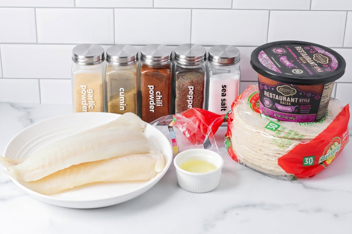 This flaky fish tacos recipe with creamy slaw is ready in just 30 minutes – perfect for quick, delicious tacos any night! Ingredients for fish tacos recipe on a kitchen counter.