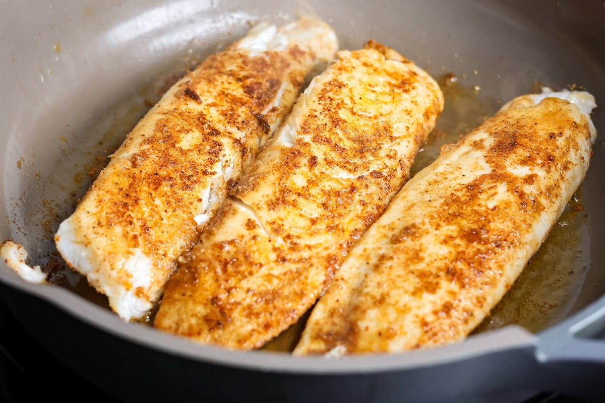 Cooking fish in a pan on the stove.