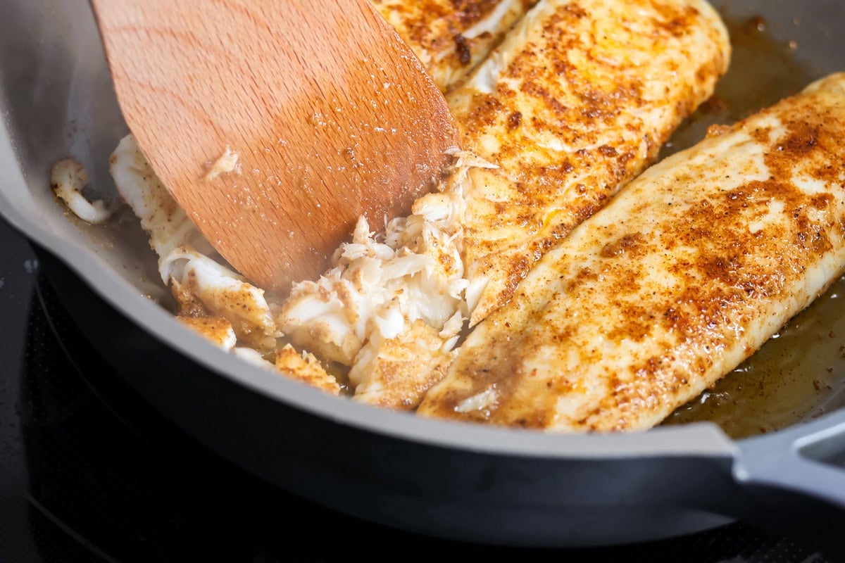 Breaking cooked fish into pieces for this fish tacos recipe.