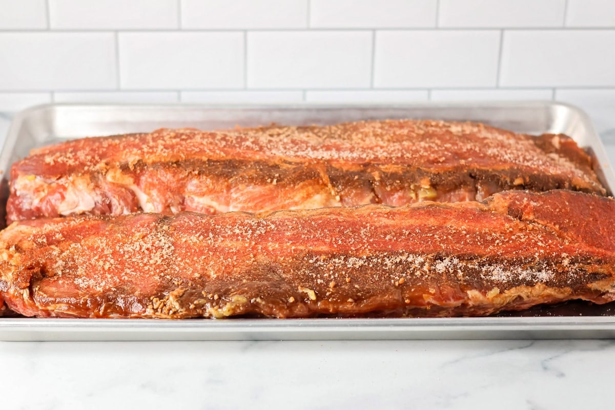 Seasoned ribs on a lined baking sheet.