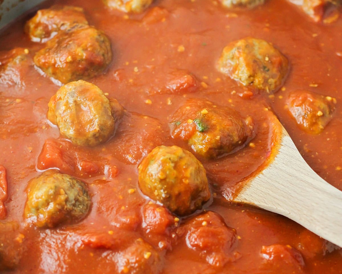 Meatballs simmering in marinara sauce.