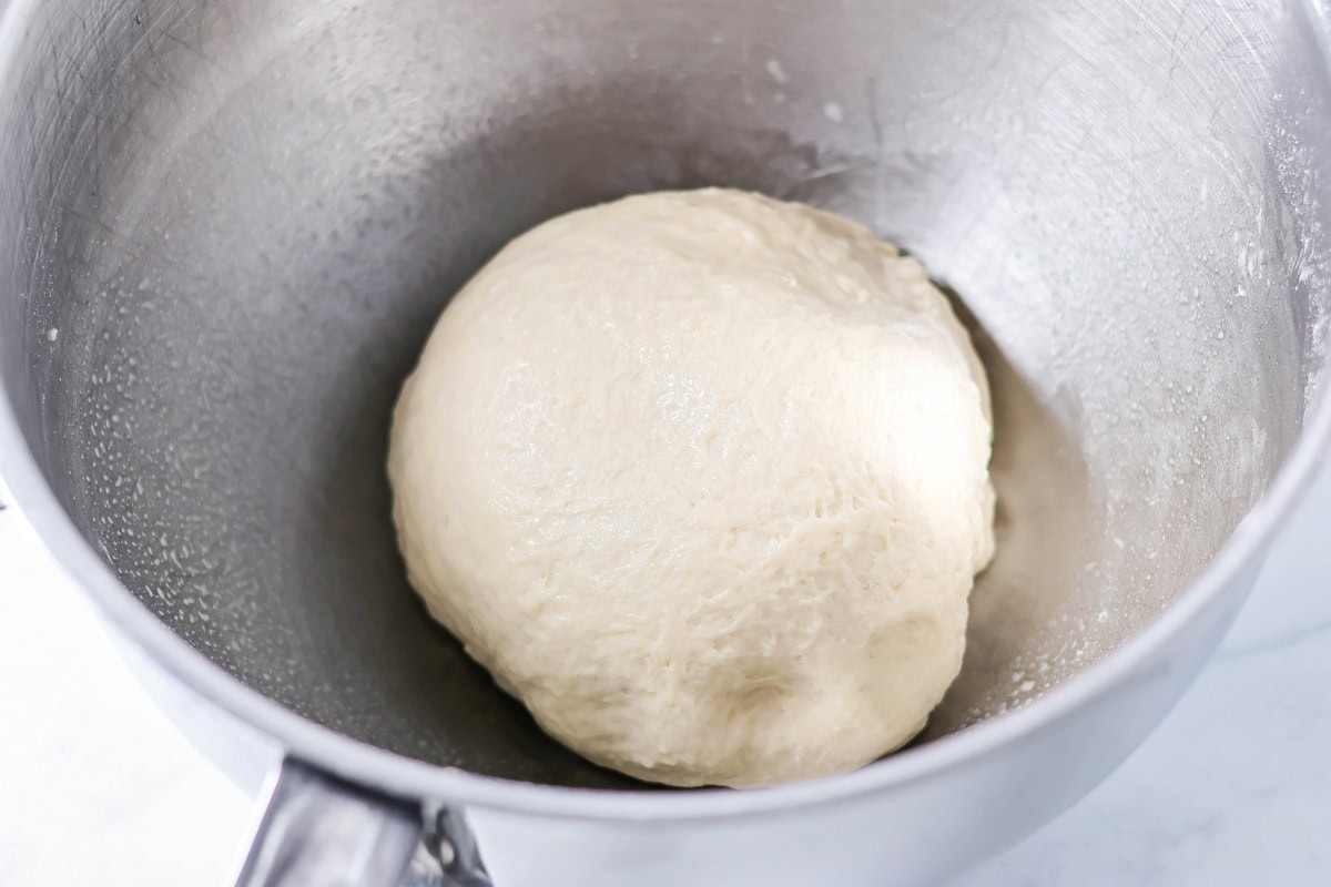 A dough ball rising in a metal bowl.