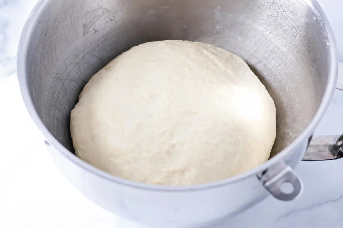A dough ball rising in a metal ball.