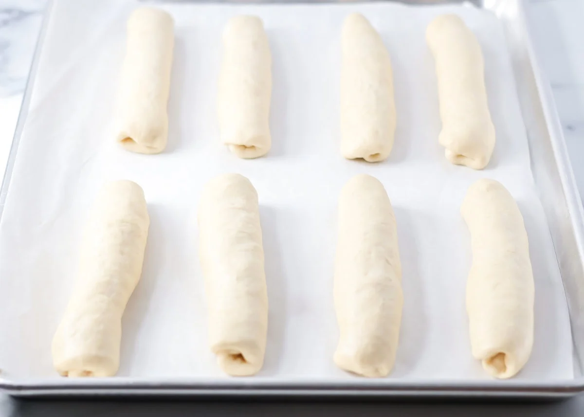 Shaped loaves on a lined baking sheet.