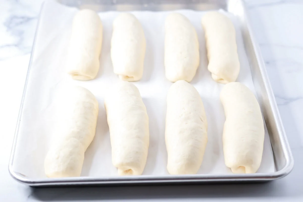 Dough loaves risen on a lined baking sheet.