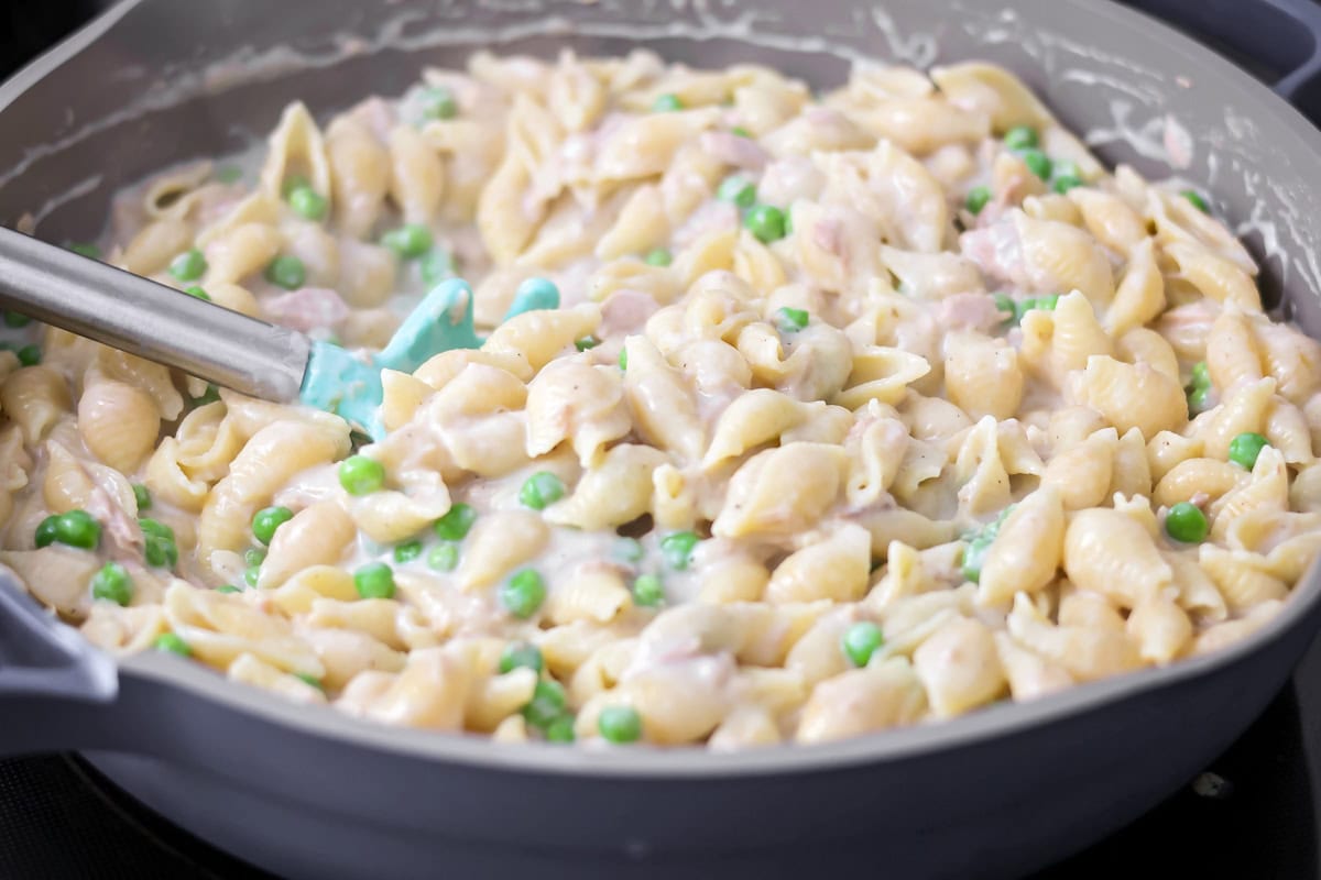 Adding pasta to the white sauce.