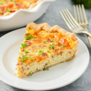 A slice of the best quiche recipe on a white plate.