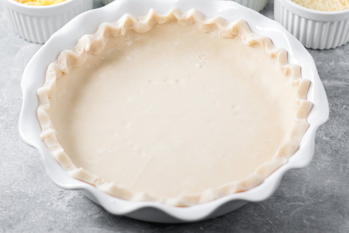 Pie crust shaped into pie dish for the base of a quiche recipe.