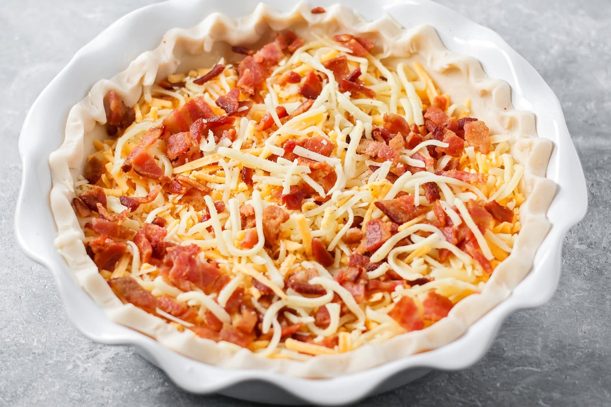 Homemade bacon quiche recipe with ingredients added to the pie crust.