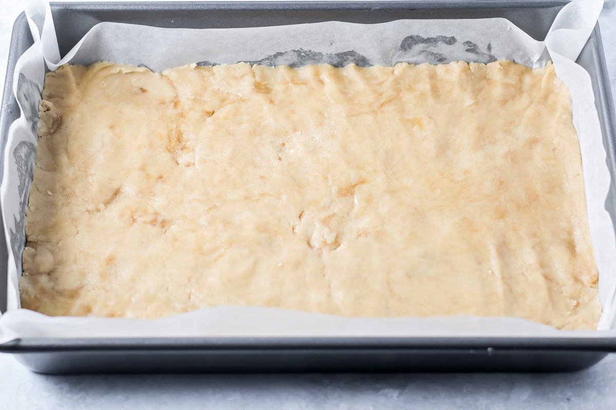 Shortbread cookie crust pressed in the bottom of a baking pan.