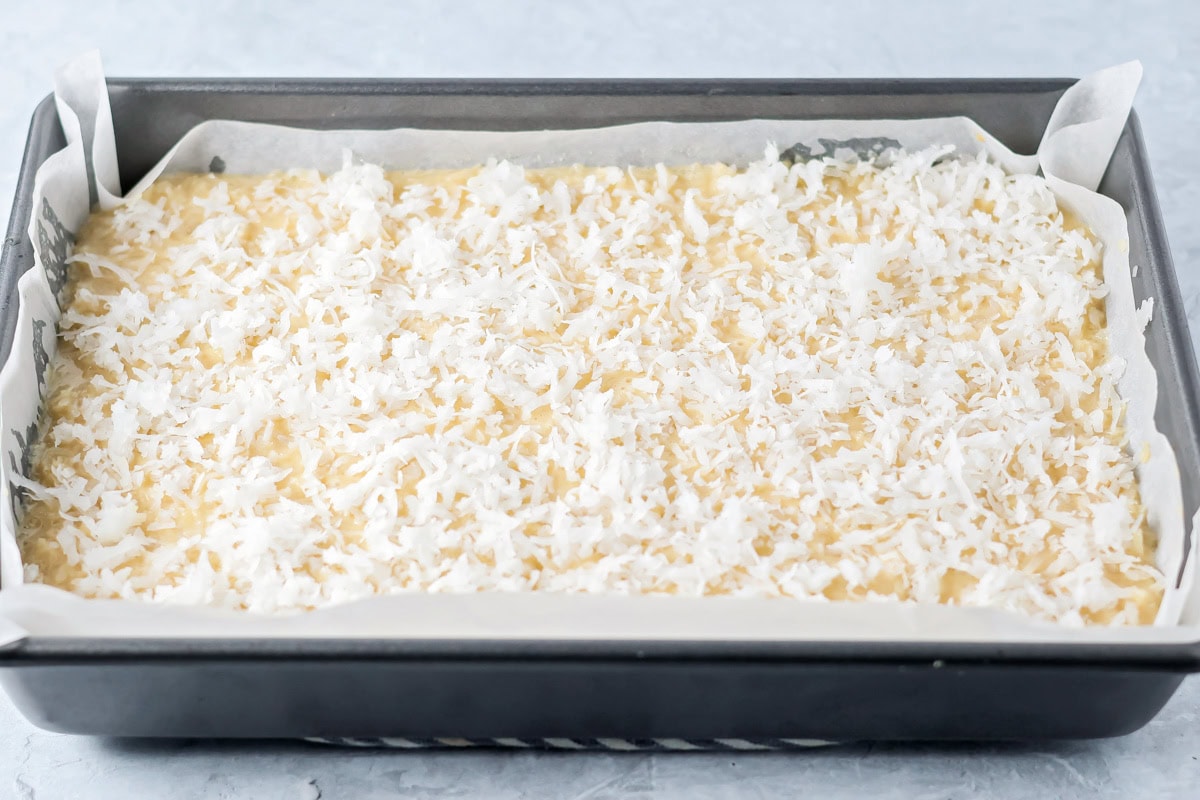 Shredded coconut on top of bars, ready to be baked.