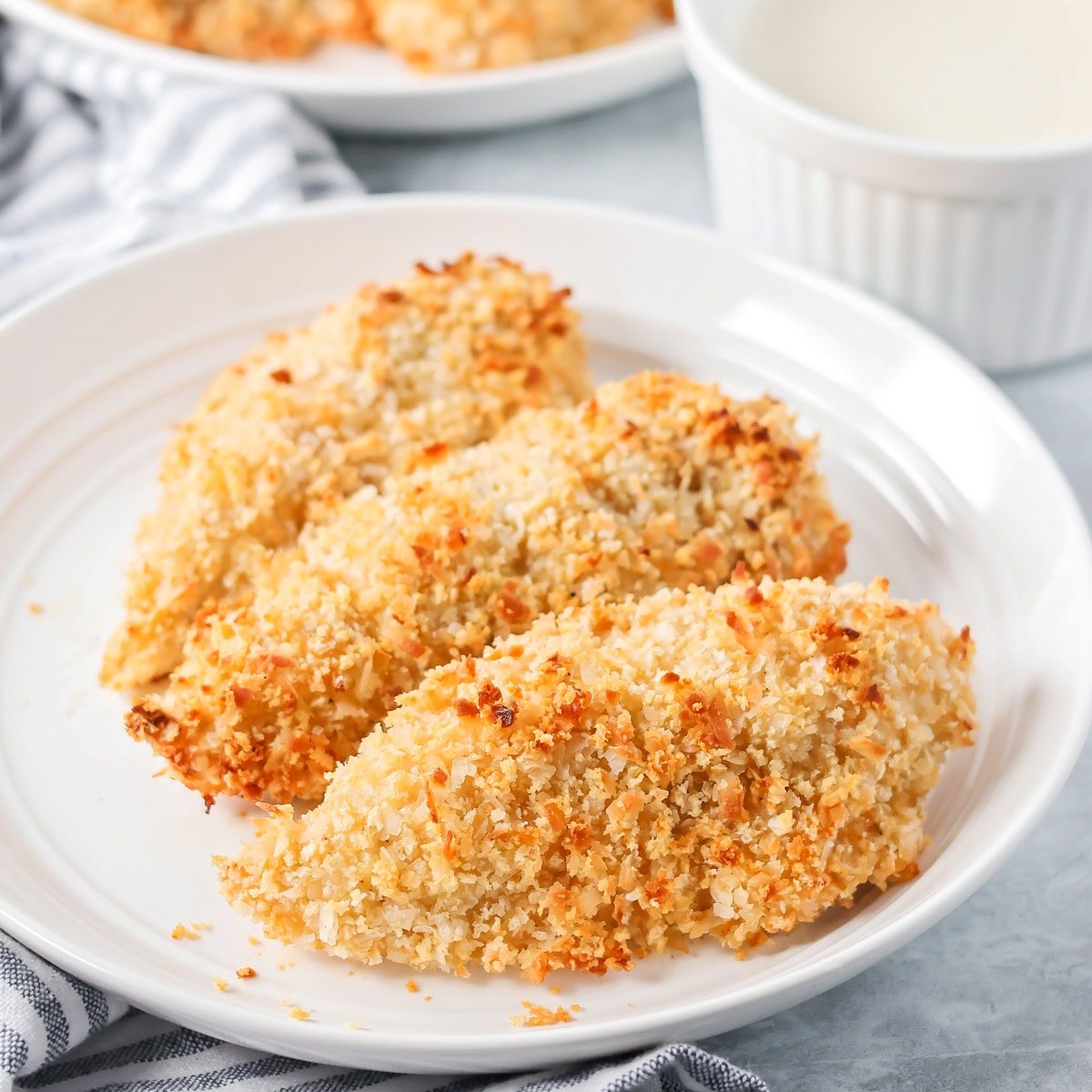 Three strips of crispy chicken on a white plate.