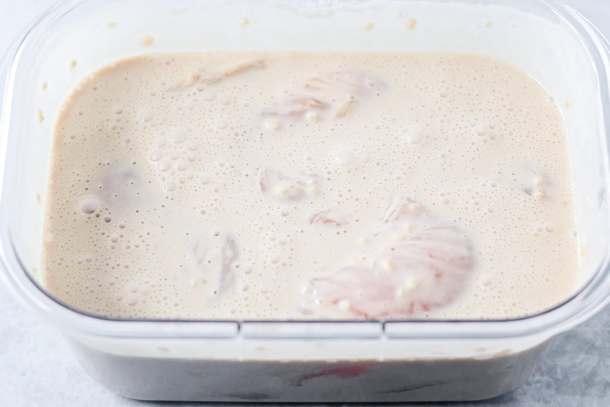 Chicken breasts marinating in coconut milk.