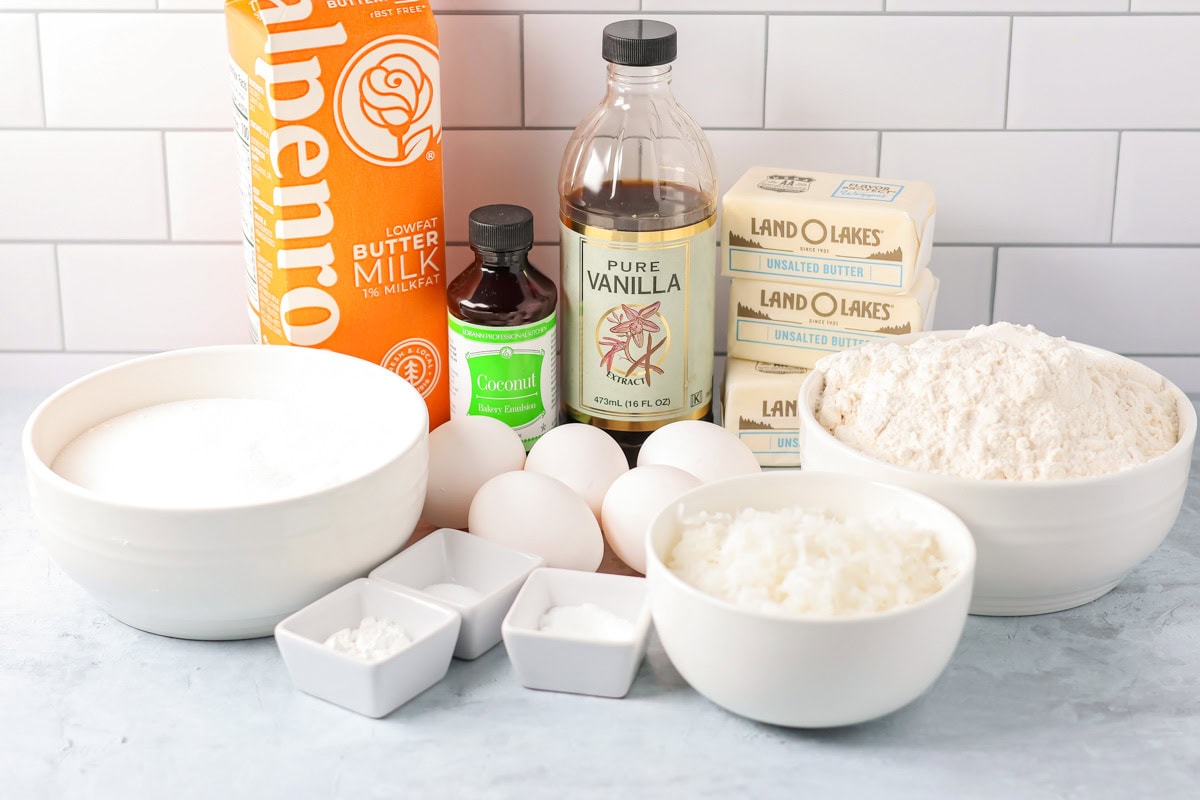 Coconut cupcakes are a tropical dream, topped with cream cheese frosting and toasted coconut for a sweet escape in every bite! Ingredients for coconut cupcakes on a kichen counter.
