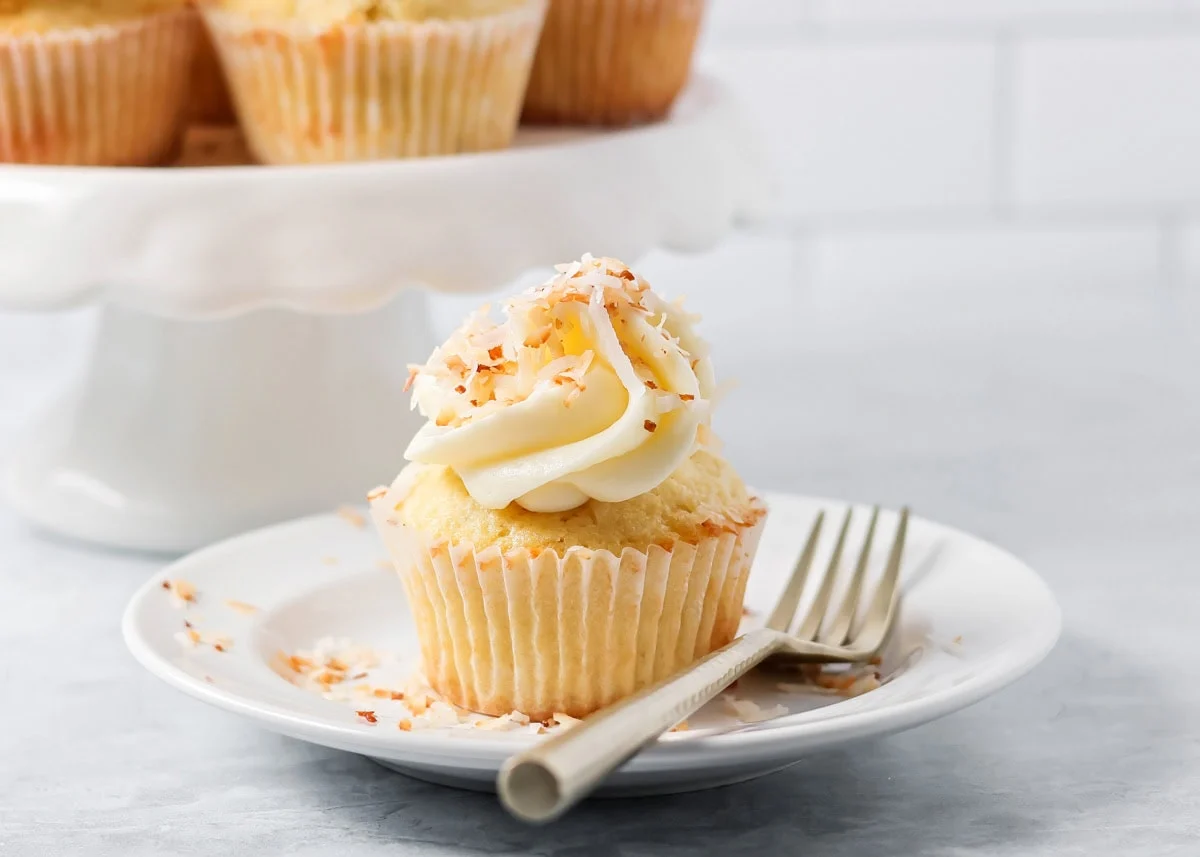 Coconut cupcake on a white plate.