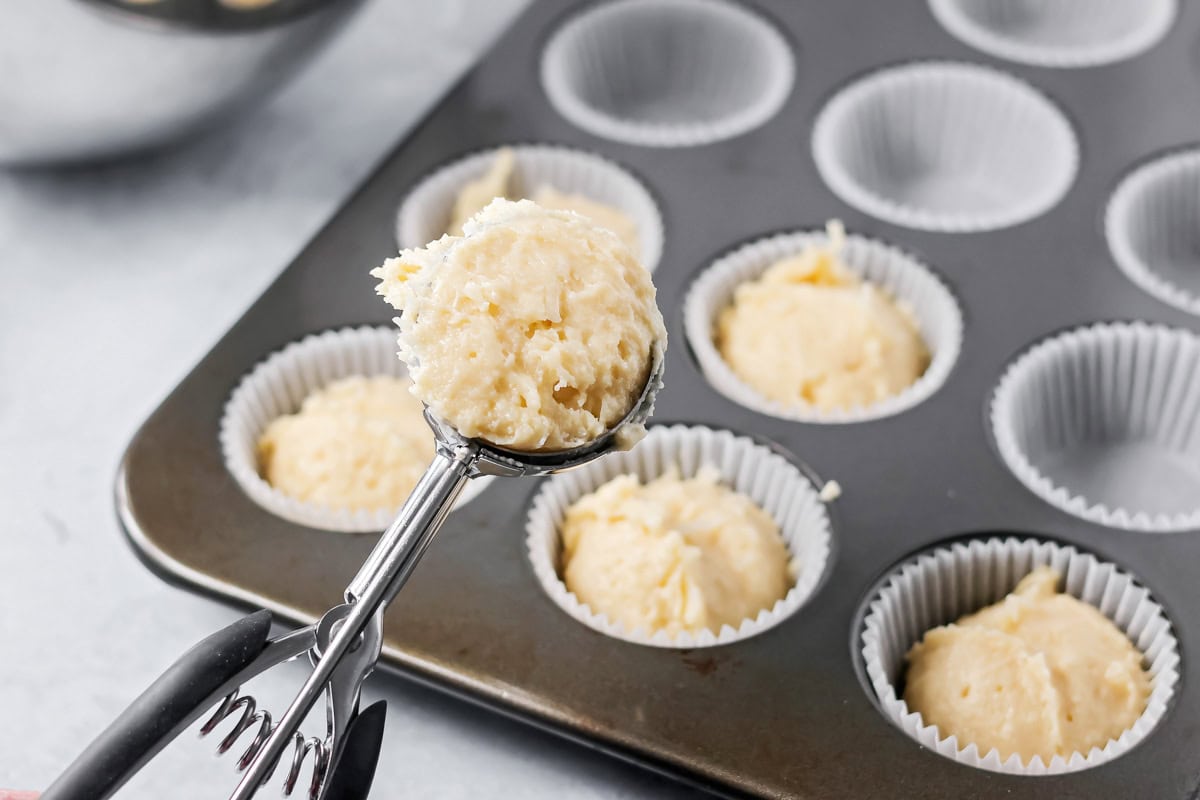 Scooping cupcake batter into liners.