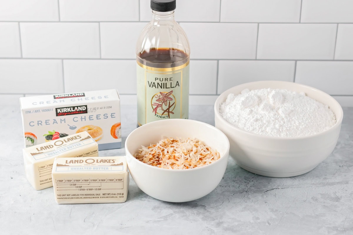 Coconut cupcakes are a tropical dream, topped with cream cheese frosting and toasted coconut for a sweet escape in every bite! Ingredients for coconut cupcake frosting on a kitchen counter.