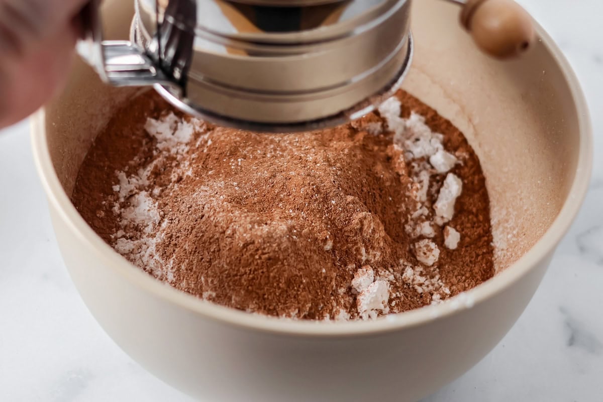 Sifting sugar and cocoa powder into a bowl.