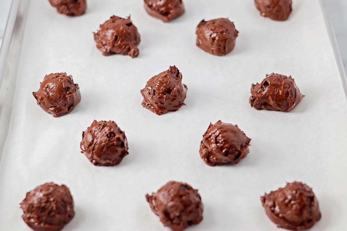 Scooped cookies on a lined baking sheet.