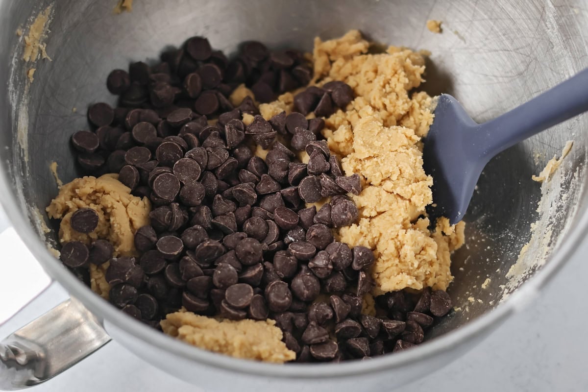 Adding chocolate chips to the cookie batter.