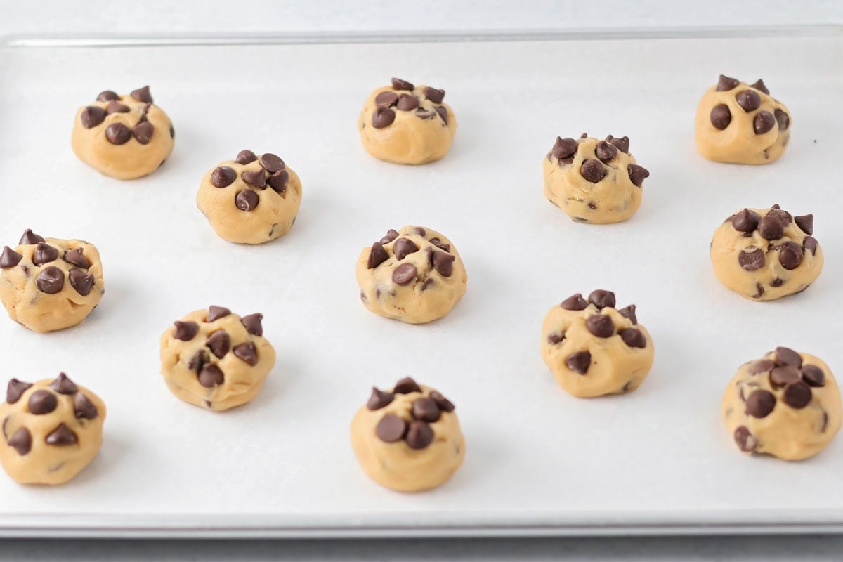 Chocolate chip cookies scooped onto a lined baking sheet.
