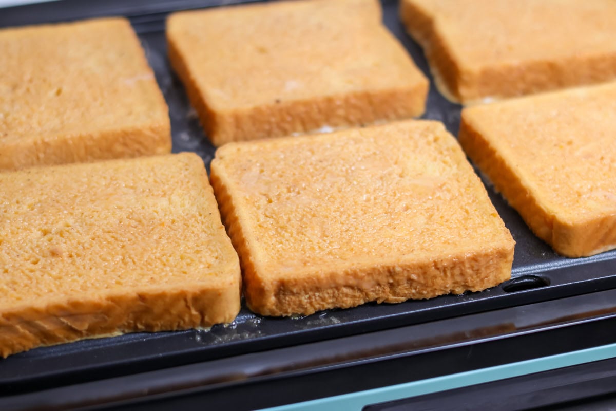 Infused with warm spices and pumpkin, this quick and easy pumpkin French toast transforms breakfast into a cozy, decadent fall favorite! Dipped french toast heating on a griddle.