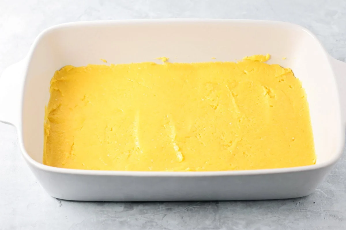 These pumpkin pie bars use a cake mix shortcut to create a fluffy, pumpkin-spiced treat that's perfect for sharing! Batter spread in a baking dish.