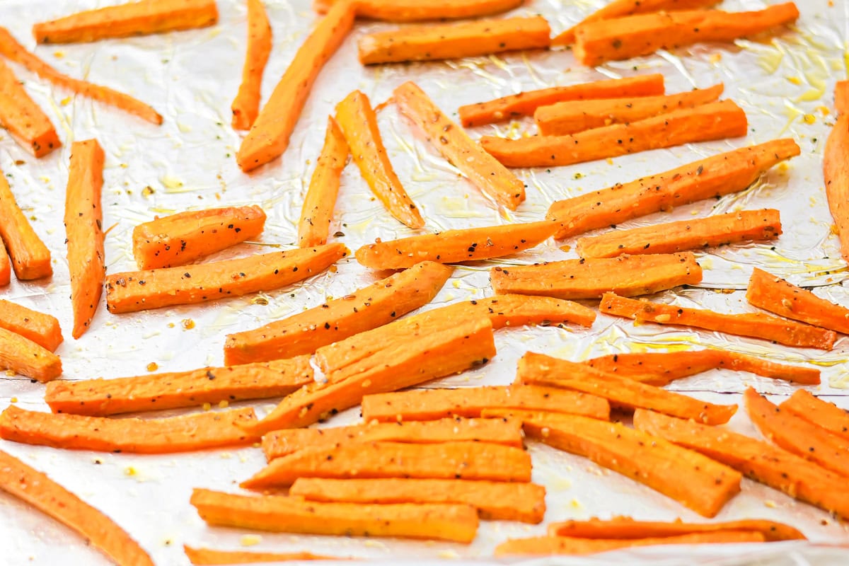 Baked sweet potato fries on a lined baking sheet.