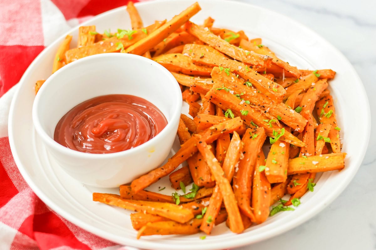 A plate of baked sweet potato fries served with ketchup.