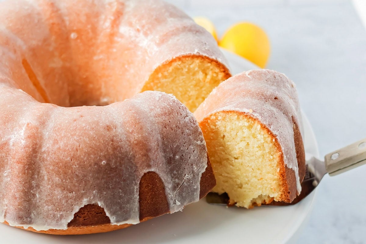 A slice being removed from a glazed bundt cake. 