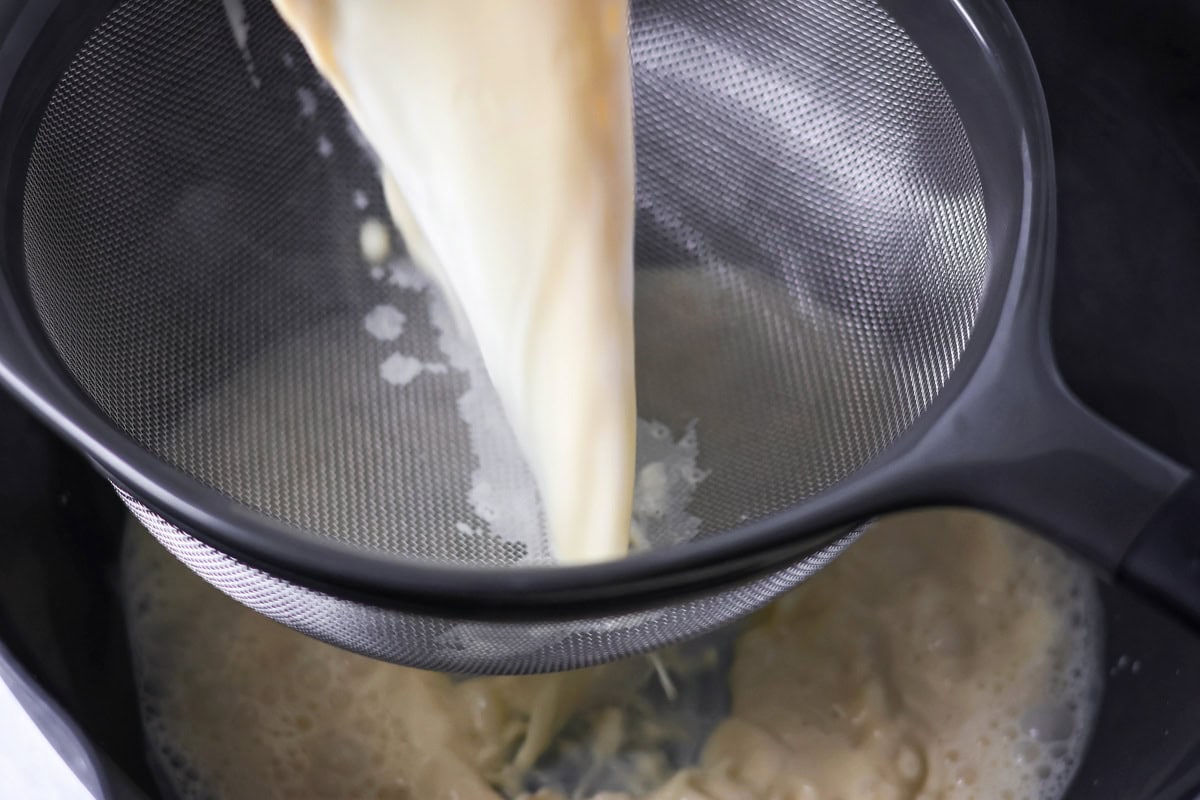 Creme brulee liquid being poured through a sieve.