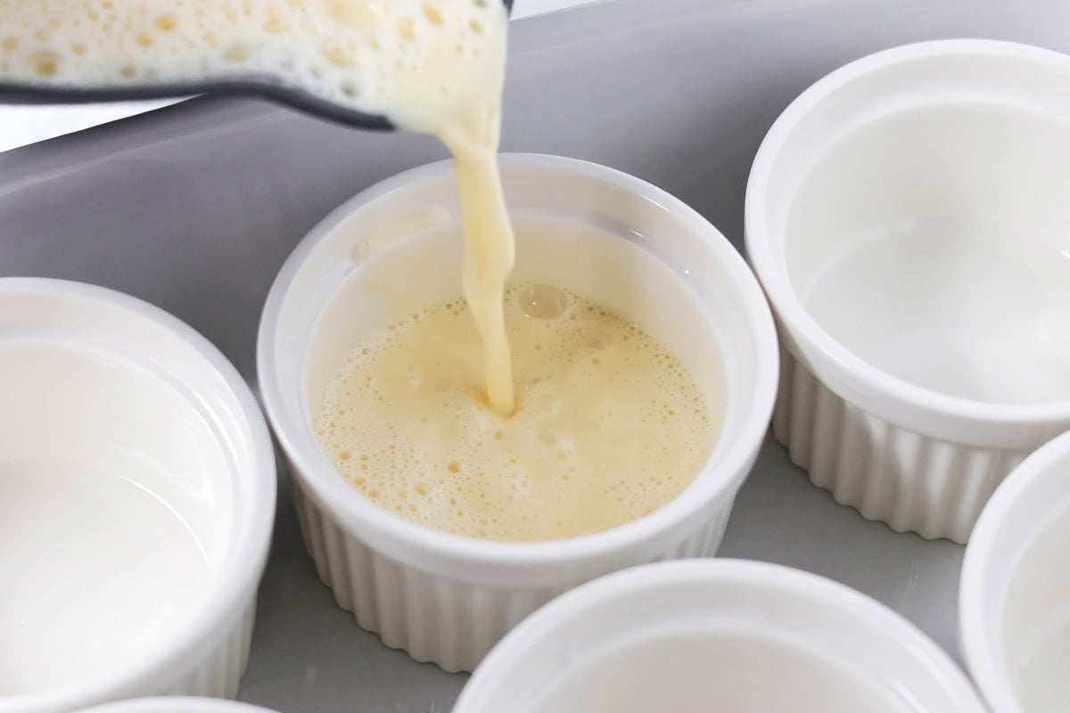 Pouring cream mixture into ramekins.