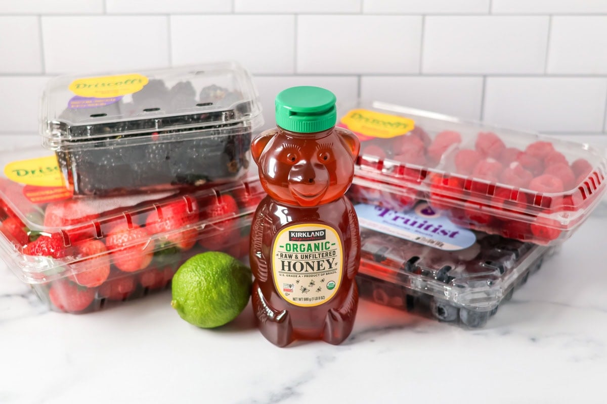 Ingredients for honey lime fruit salad on a kitchen counter.