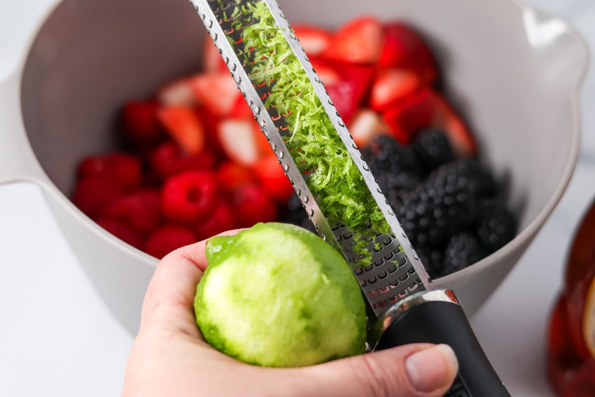 Zesting a lime over a bowl of berries.
