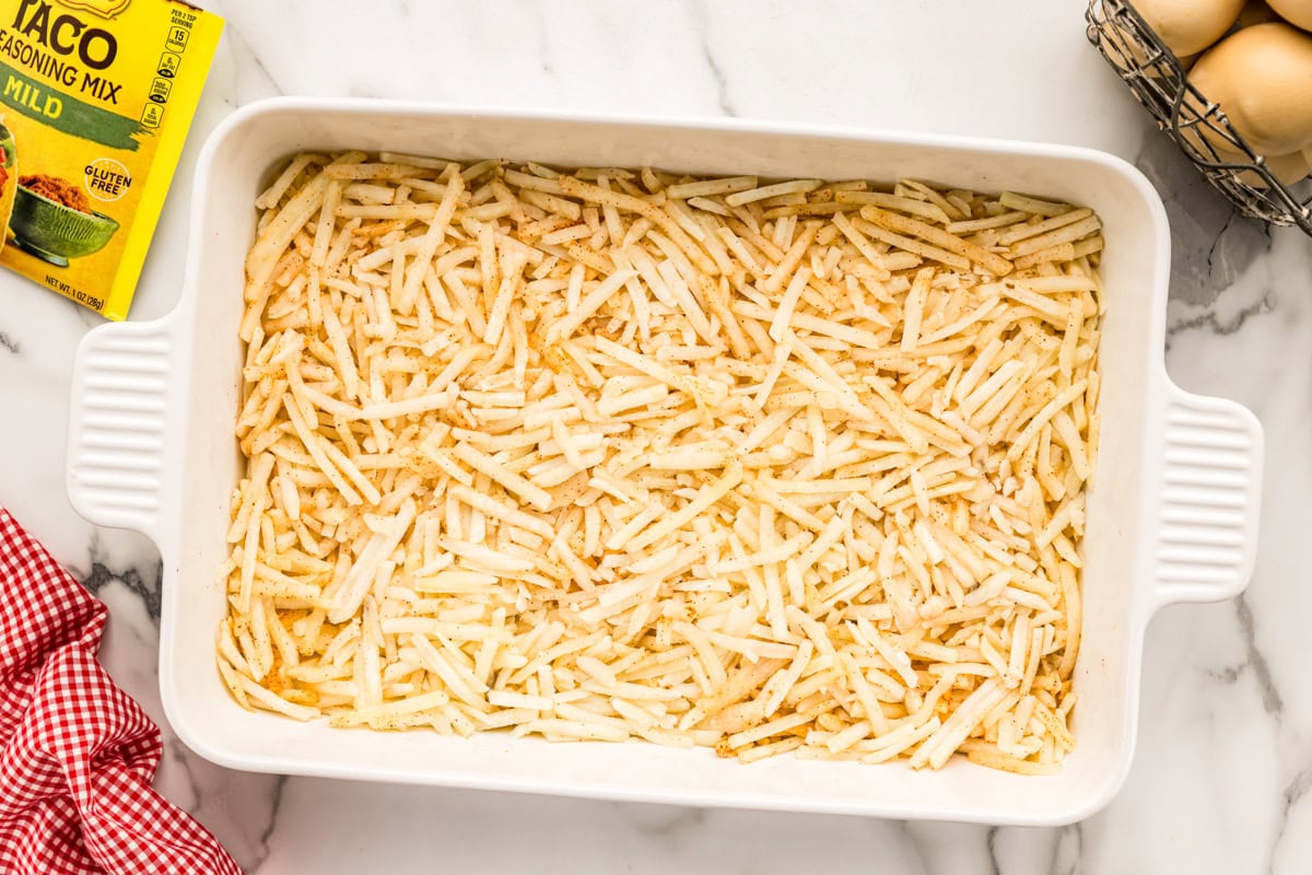 A layer of hash browns in a white casserole dish.