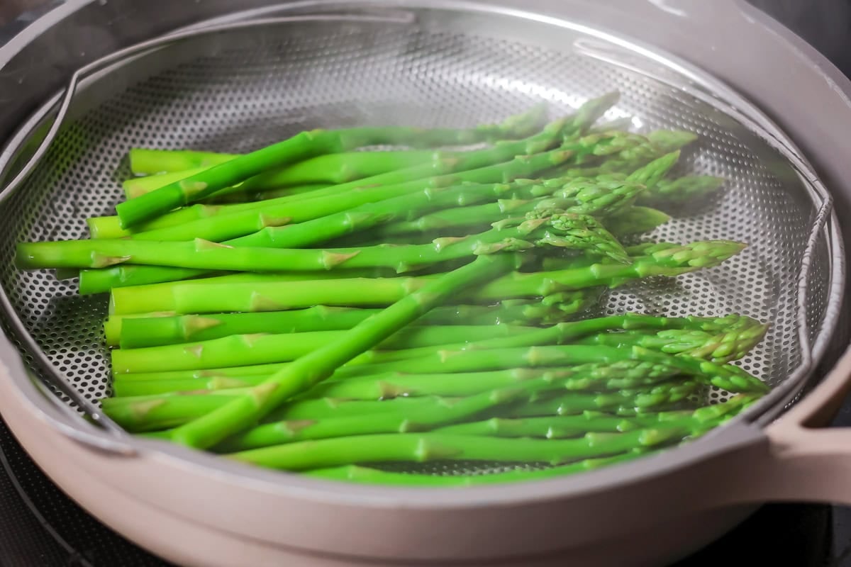 A bunch of asparagus spears in a steamer basket.