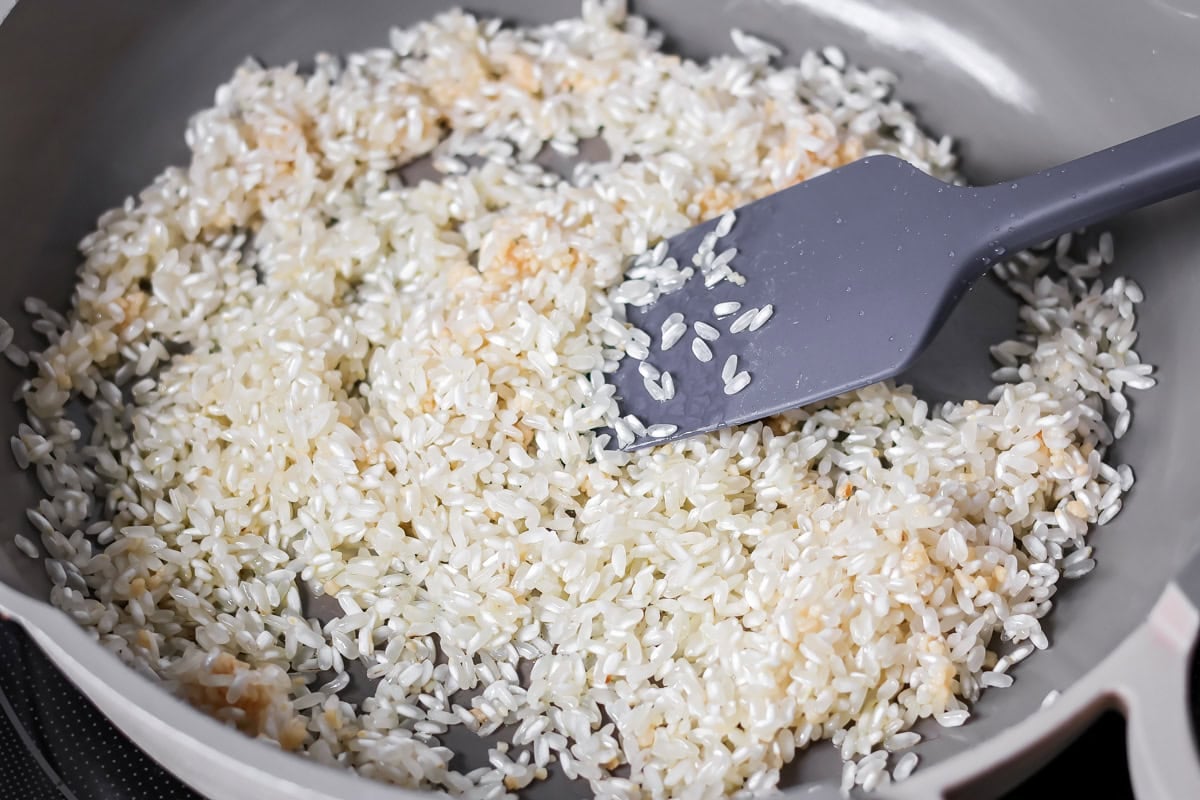 Rice being lightly toasted in a skillet.