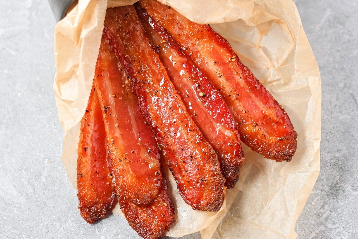This 3-ingredient candied bacon is the perfect balance of sweet and salty and the ultimate upgrade to any gathering. A set of 6 candied bacon strips wrapped in a piece of parchment paper.