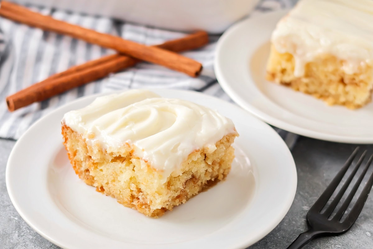 A slice of cinnamon roll poke cake on a white serving plate.