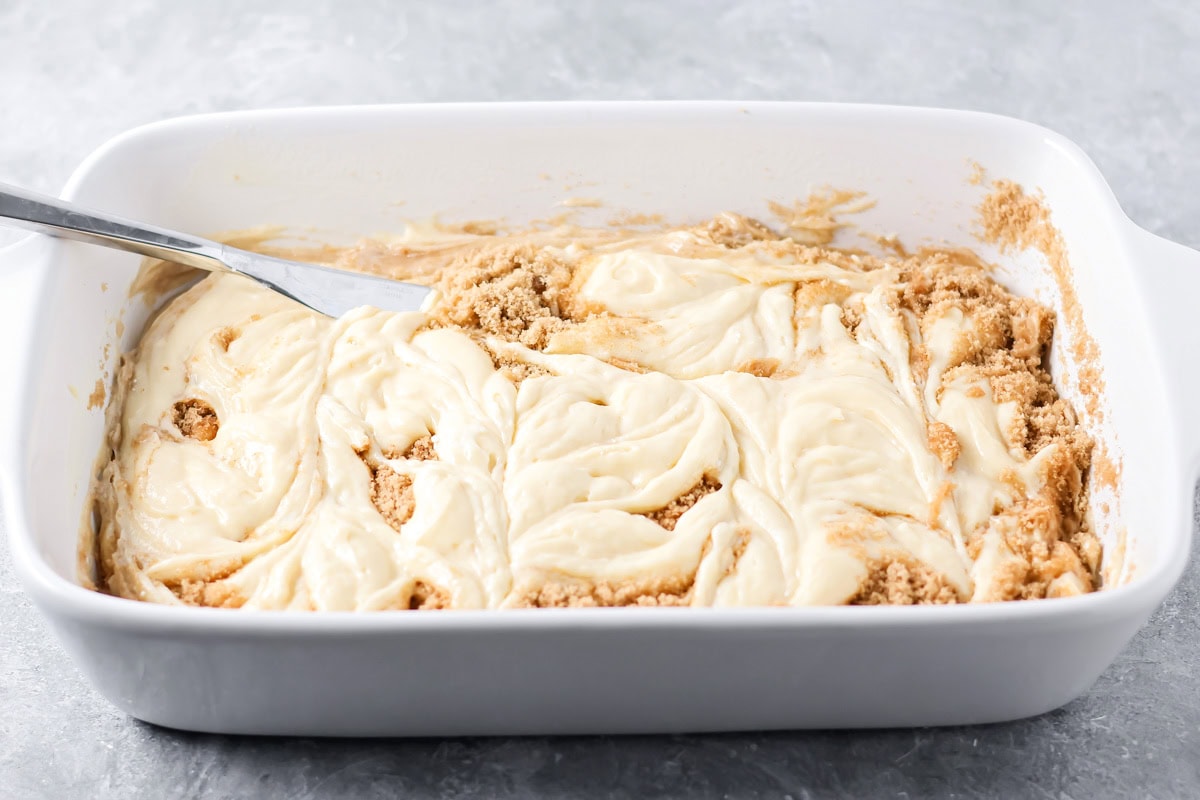 A butter knife swirling the dollops of batter into the cinnamon sugar mixture.