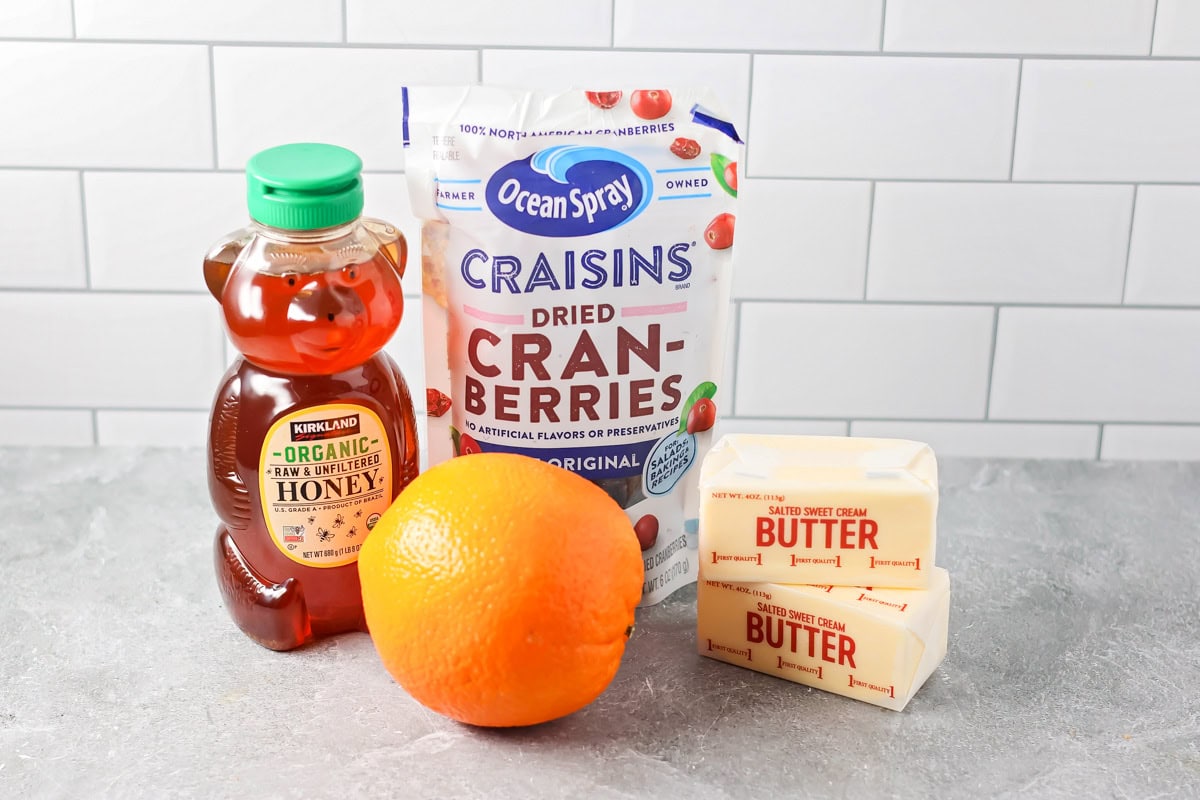 Using just 4 ingredients, this cranberry honey butter will add a delightful touch to toast, muffins, and more. Ingredients to make cranberry honey butter on a kitchen counter.